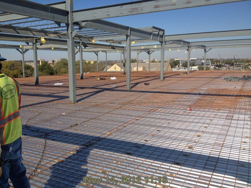 A construction worker is standing on a slab on deck concrete floor
