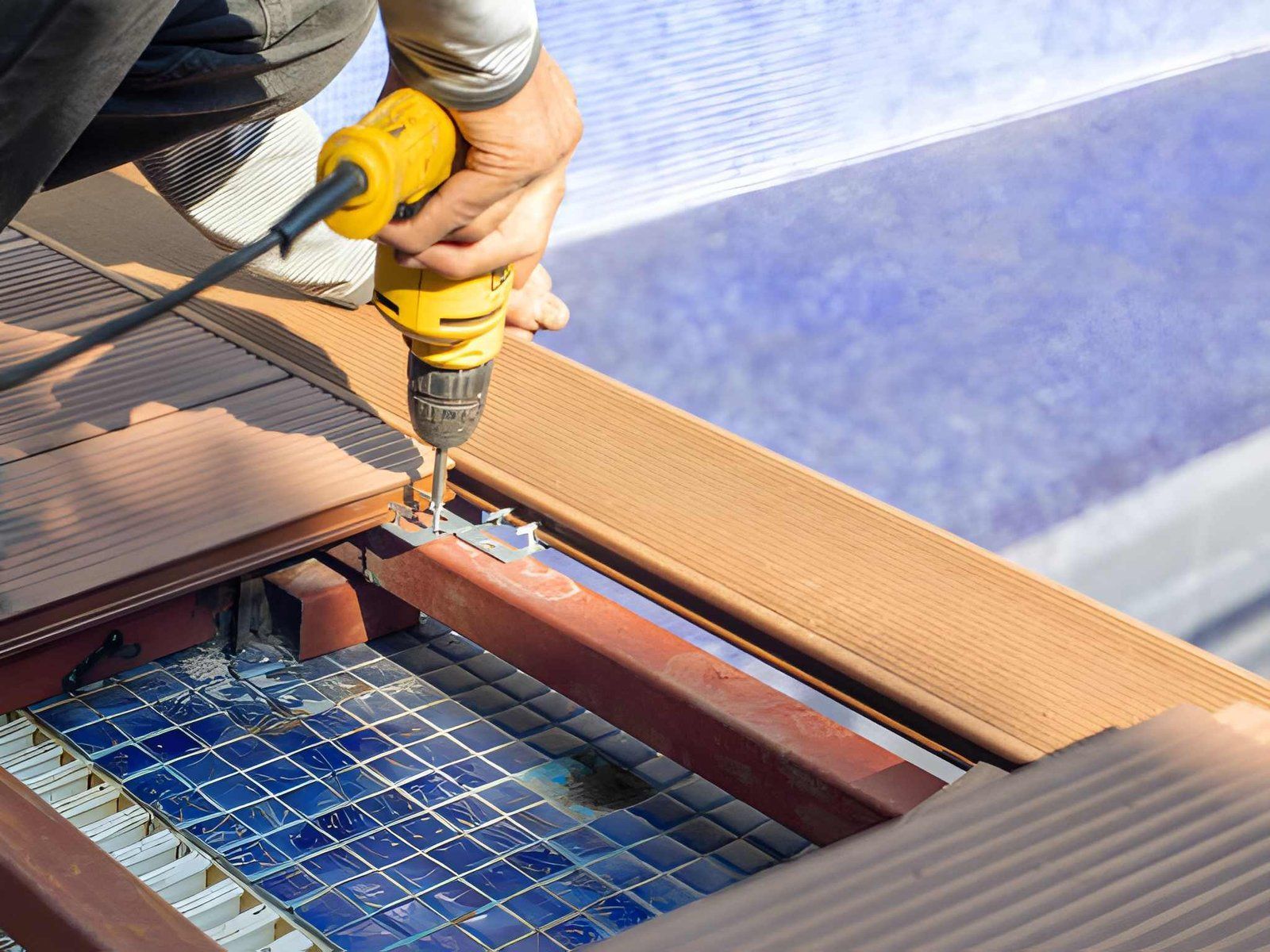 Worker drilling a hole in a rooftop solar panel frame with a yellow power drill