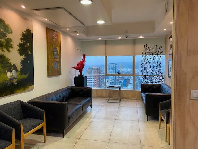 Recepcionista atendiendo a dos clientes en la recepción de una oficina moderna