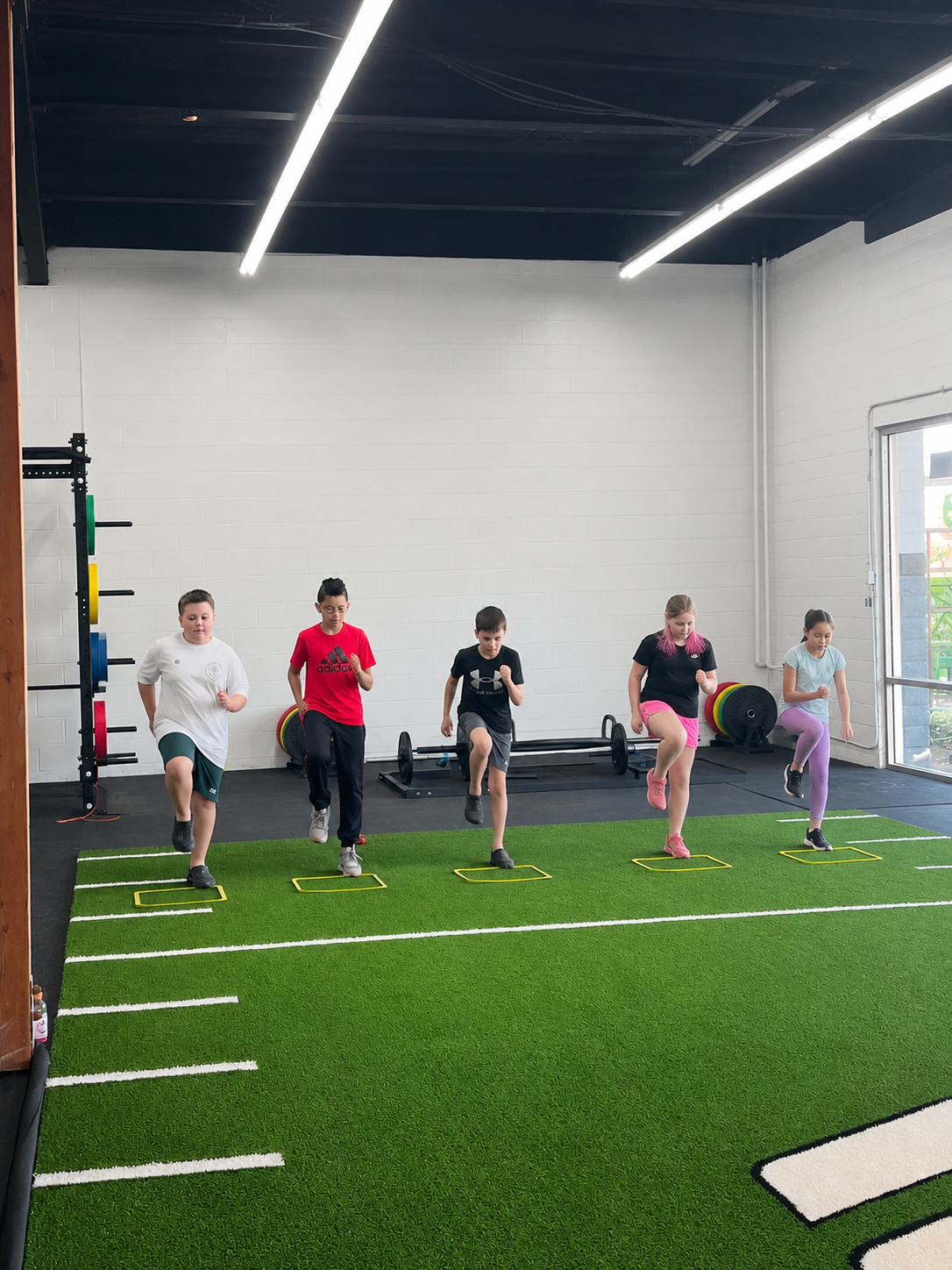 Children doing agility drills with a coach in the gym kids zone