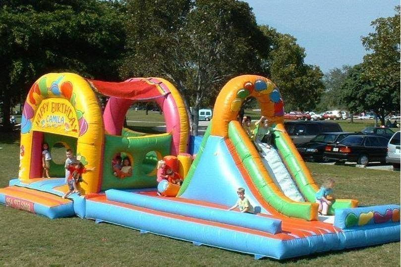 Colorful inflatable bounce house and slide at an outdoor park with children playing