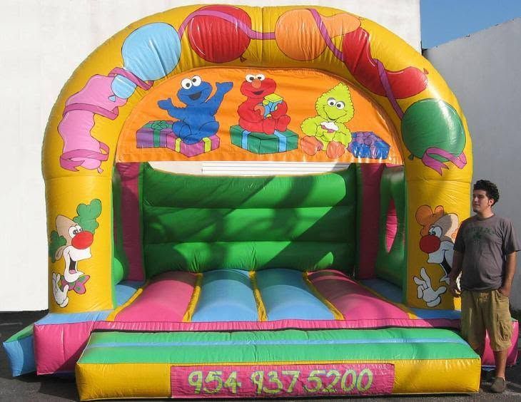 Colorful inflatable bounce house with cartoon characters and a man standing beside it
