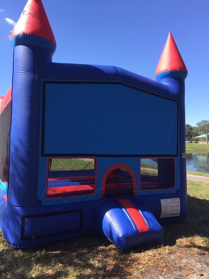 Blue bounce house castle with red cone towers and a front entry opening outdoors on grass