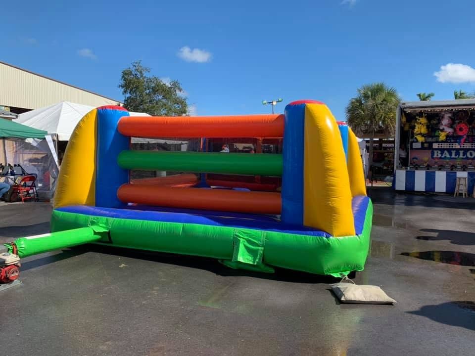 Colorful inflatable bounce house on pavement outside a building under a clear blue sky