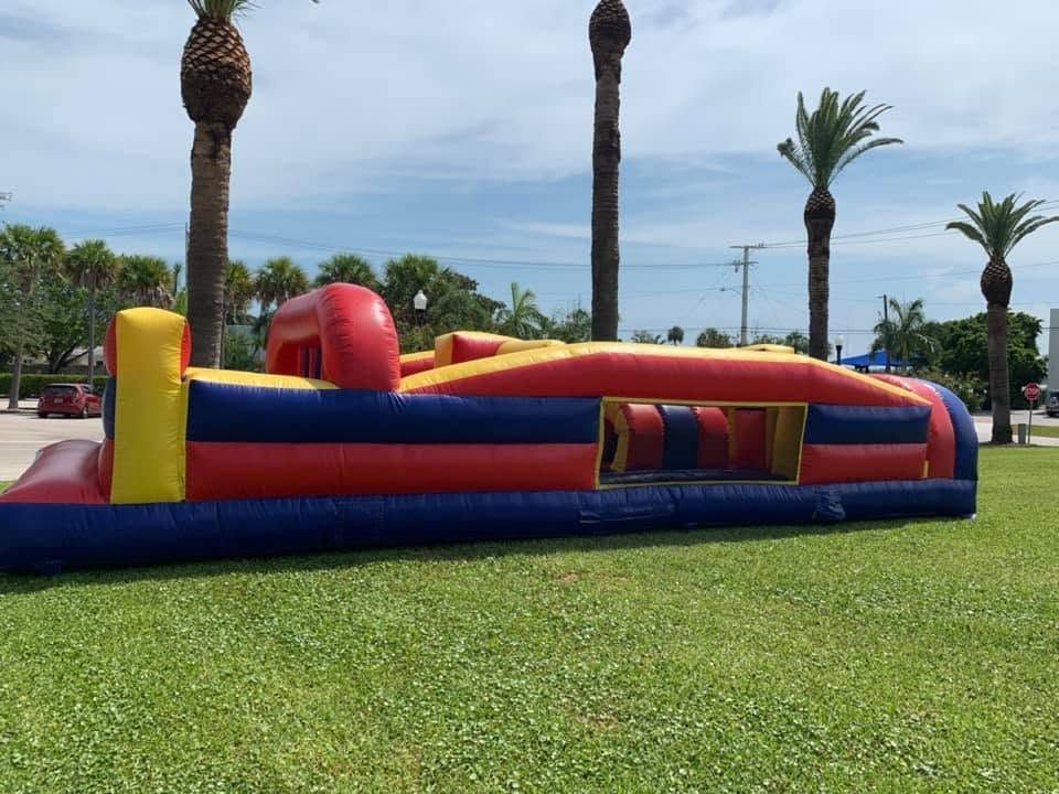 Colorful inflatable bounce house on a grassy lawn with palm trees and ocean in the background