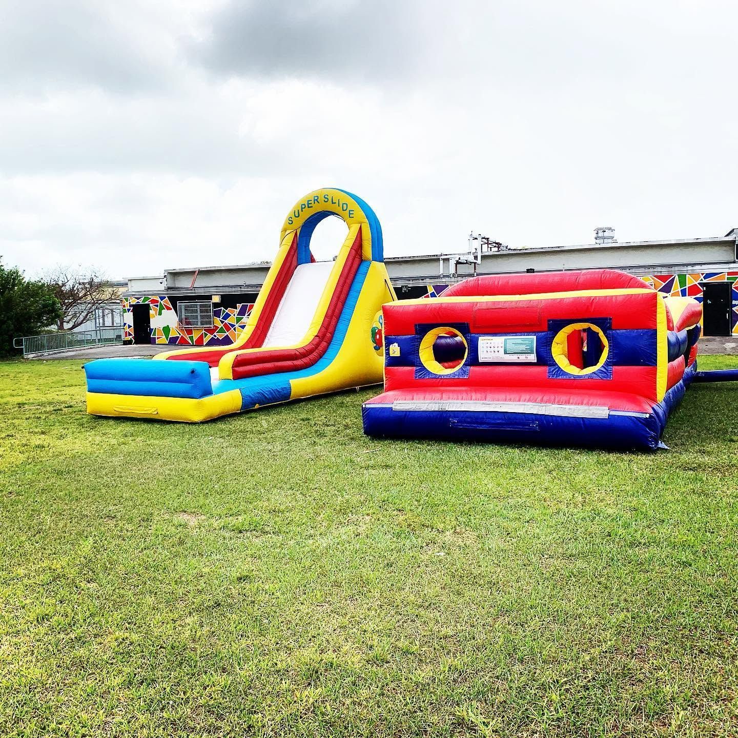 Colorful inflatable slide and bounce house on a grassy field under cloudy skies