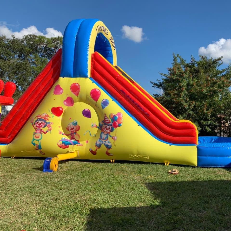 Colorful inflatable bounce slide with cartoon graphics on a grassy lawn under a blue sky