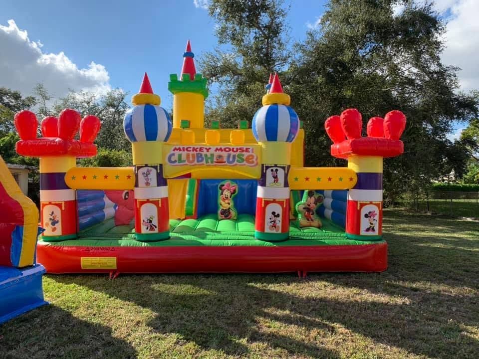 Colorful inflatable bounce castle with towers and slides set up on grass outdoors under a blue sky
