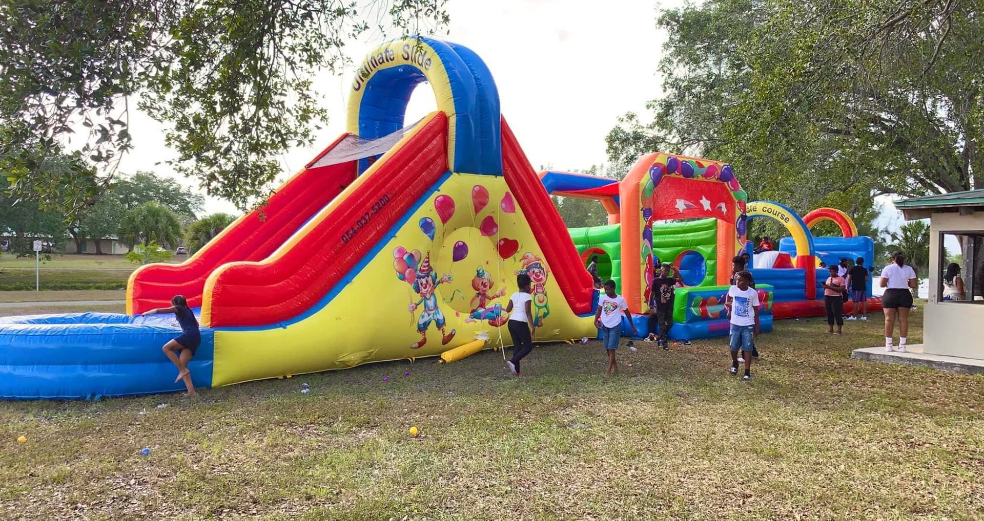 Kids playing on a colorful inflatable obstacle course and slide in a park