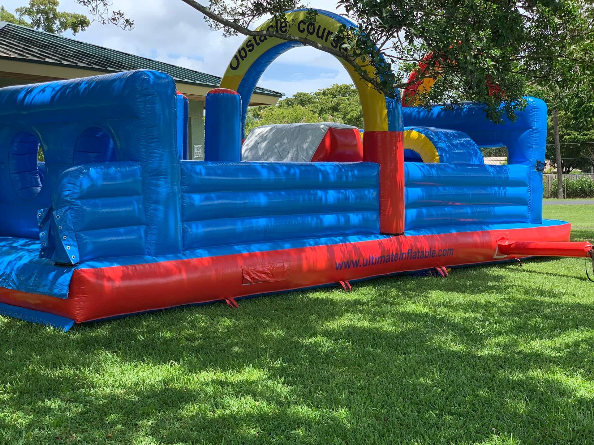 Blue and red inflatable bounce house in a grassy yard under trees