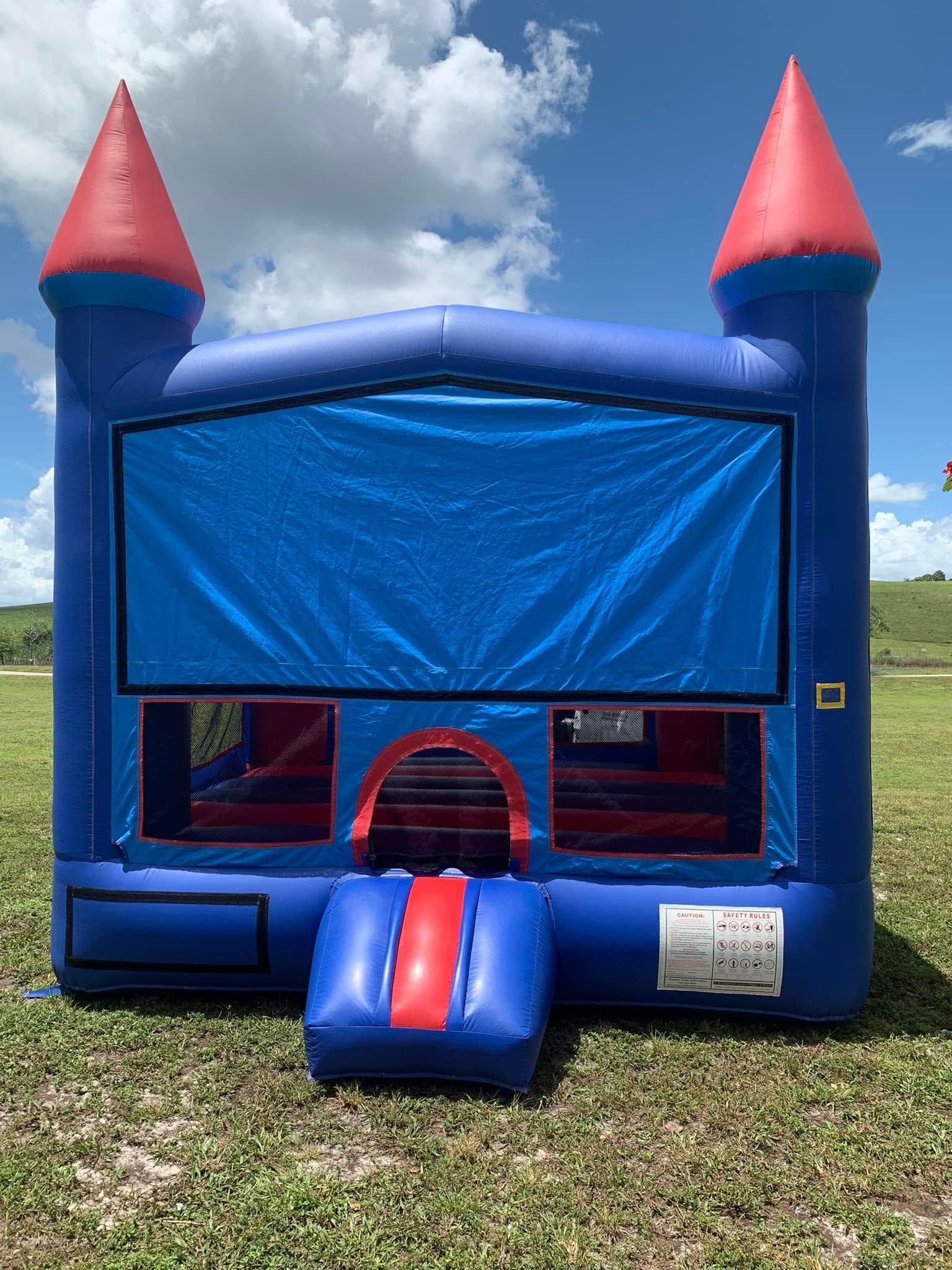 Blue and red inflatable bounce house with front slide outdoors on grass under a cloudy sky