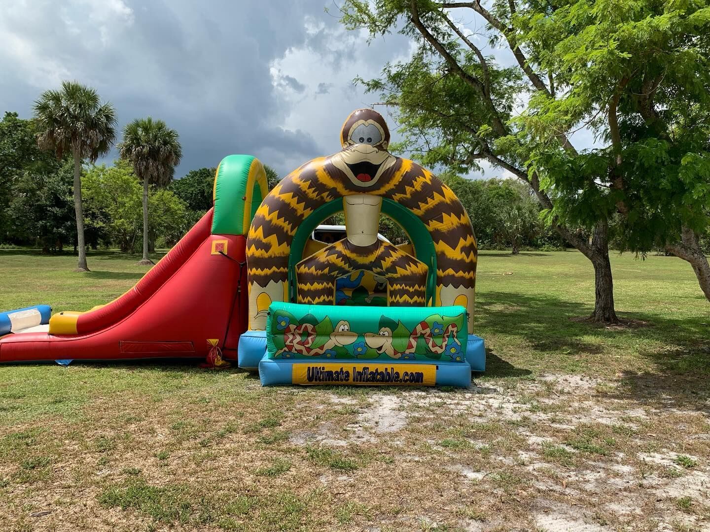 Colorful inflatable kids' obstacle course and slide on grass in a park under cloudy skies