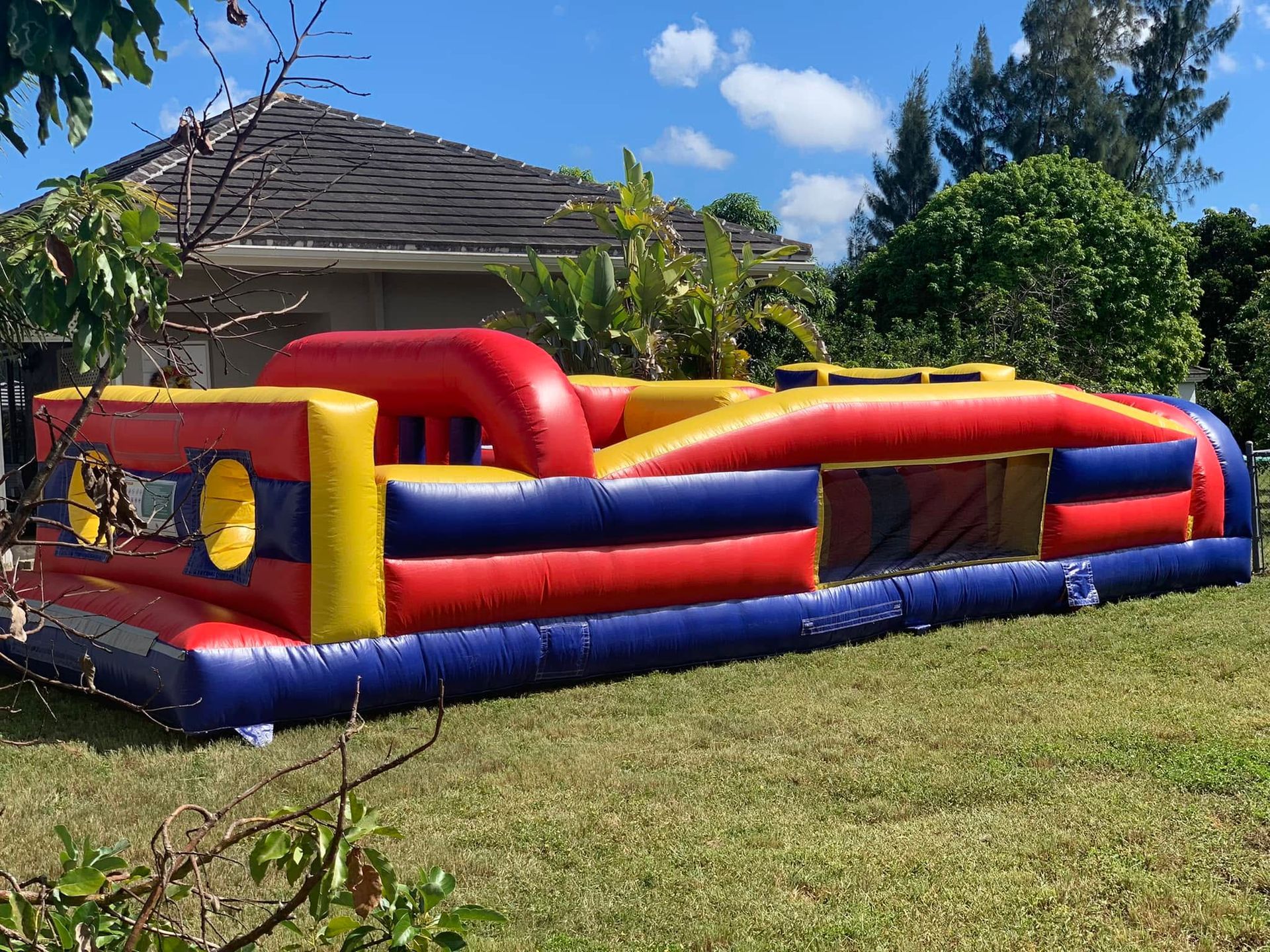 Colorful inflatable obstacle course on a grassy lawn beside a house under a blue sky