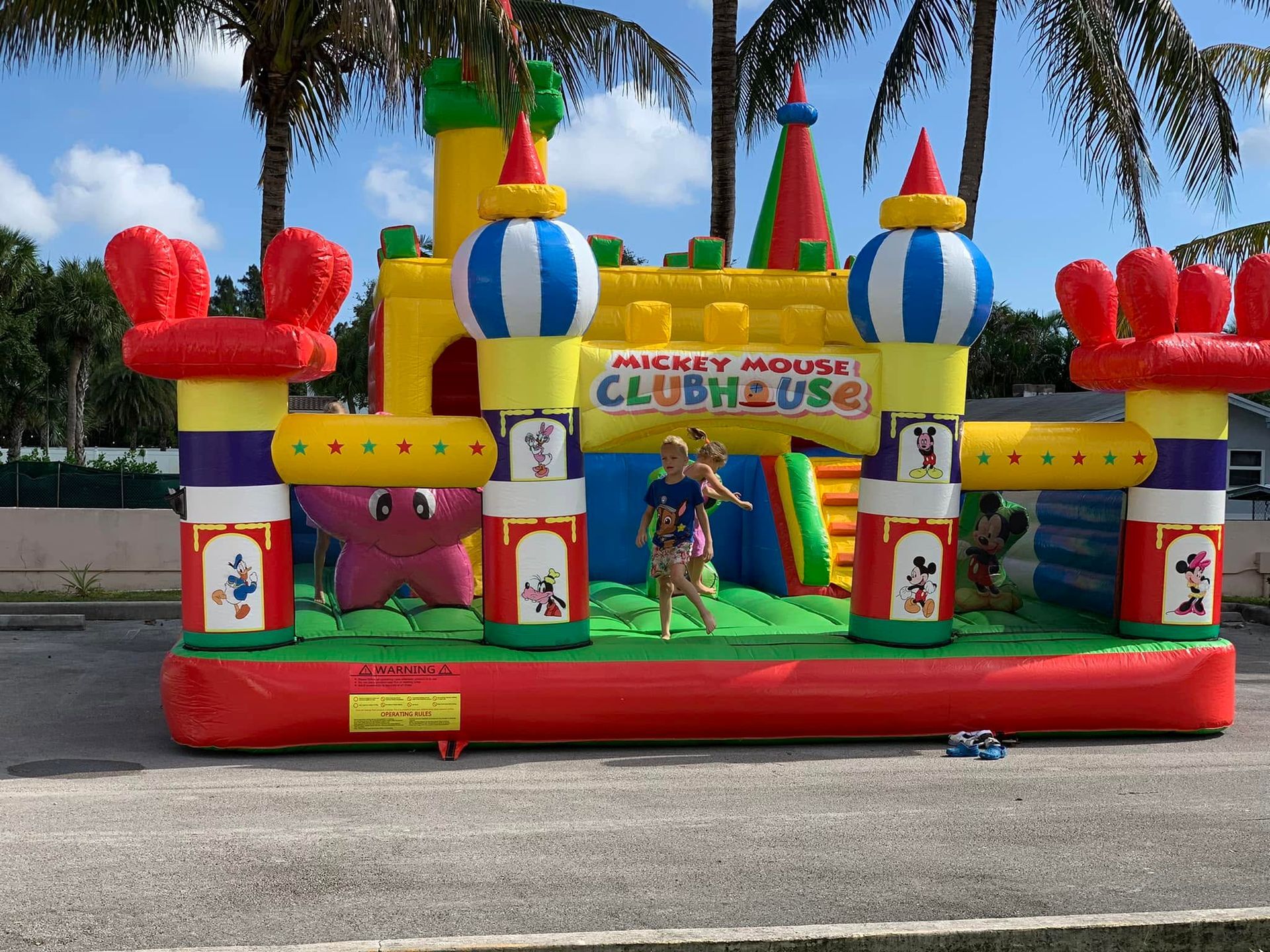 Colorful Mickey Mouse Clubhouse inflatable bounce house with a child playing inside outdoors