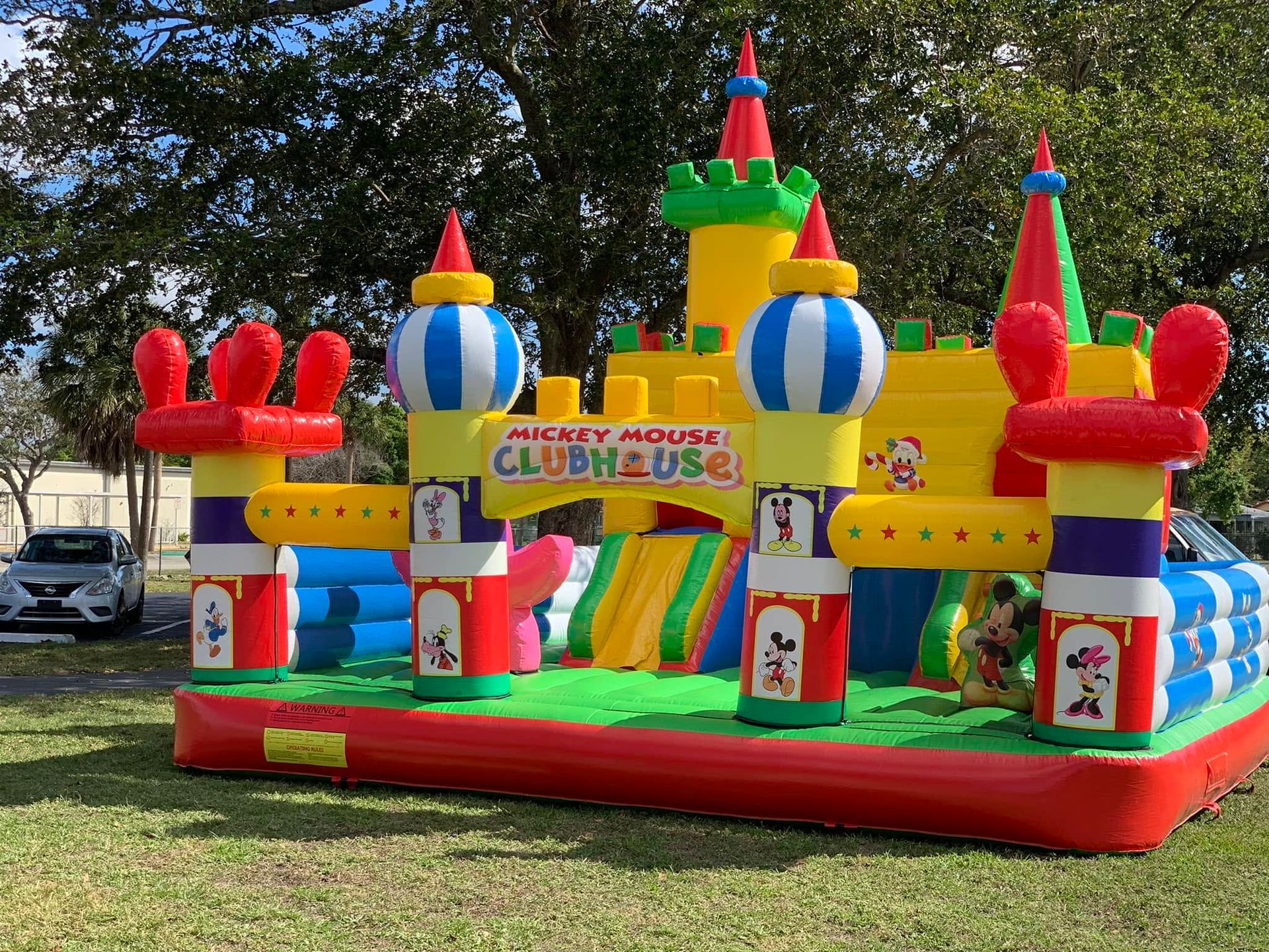 Colorful Mickey Mouse Clubhouse bounce house with red, yellow, blue, and green towers outdoors