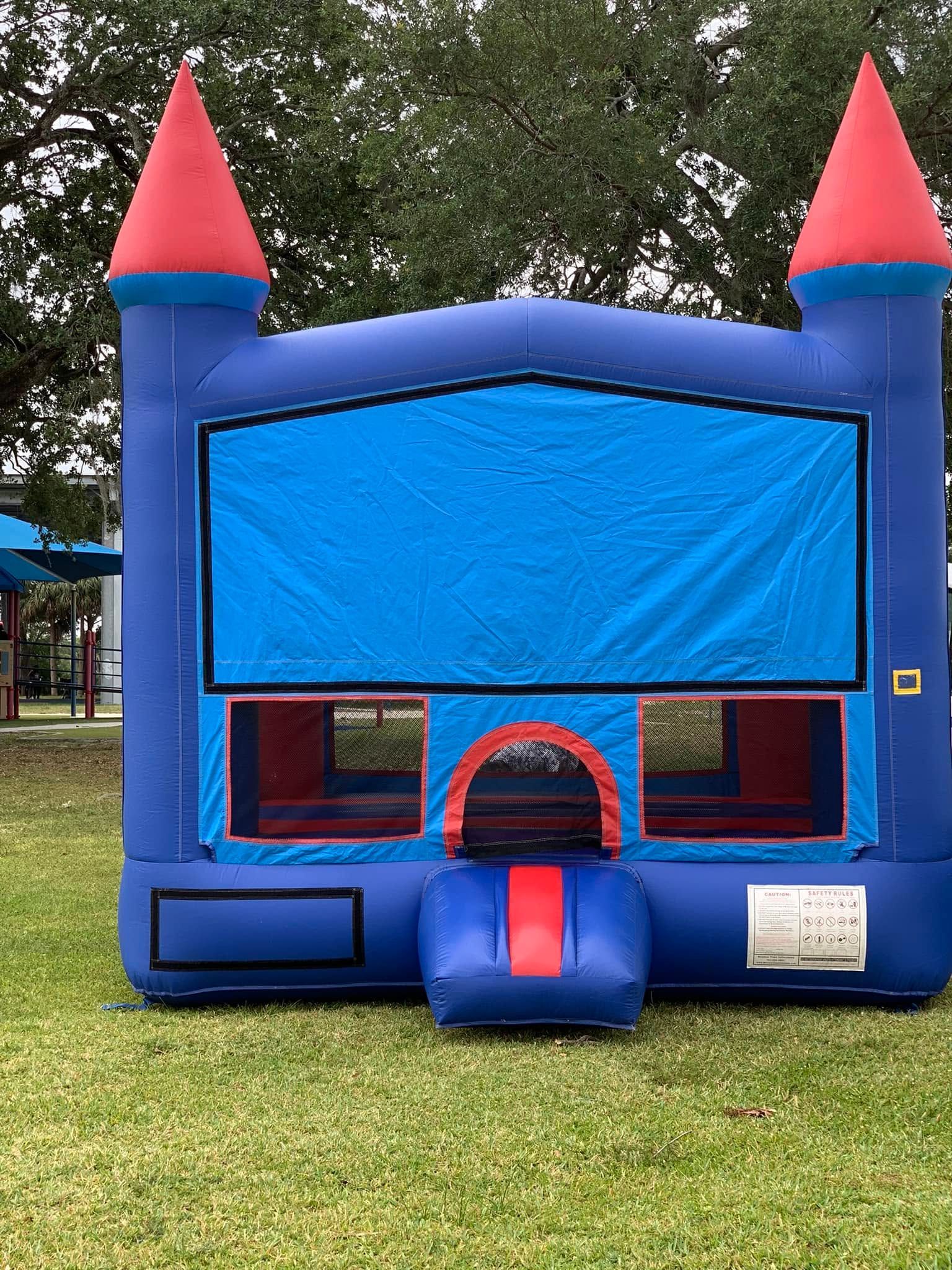 Blue inflatable bounce house with red cone towers and a front entrance on grass outdoors