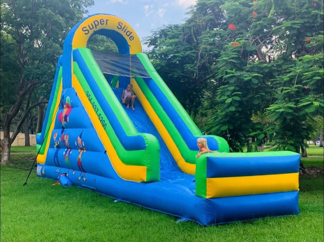 Colorful inflatable slide in a park, with children climbing and sliding.