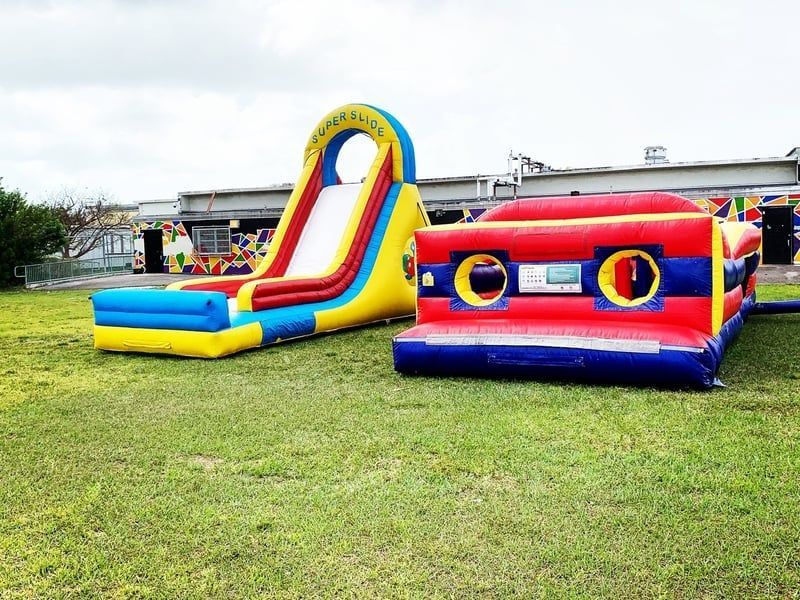 Colorful inflatable slide and bounce house on a grassy field at an outdoor event