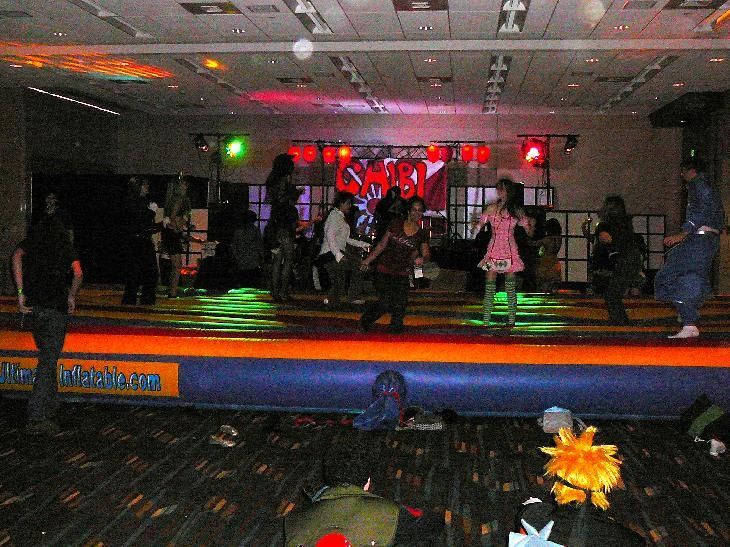 People dancing in a dim nightclub with colorful stage lights and a low barrier in front