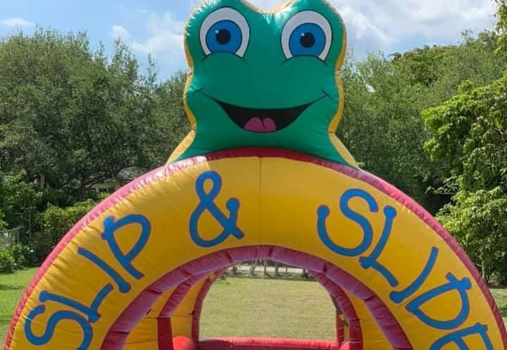 Colorful frog archway with “Slip & Slide” lettering in a grassy outdoor park