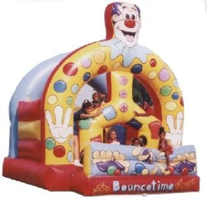 Clown-themed inflatable bounce house with children inside, red and yellow with colorful polka dots