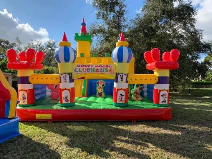 Colorful inflatable castle bounce house outdoors on a grassy lawn under a blue sky