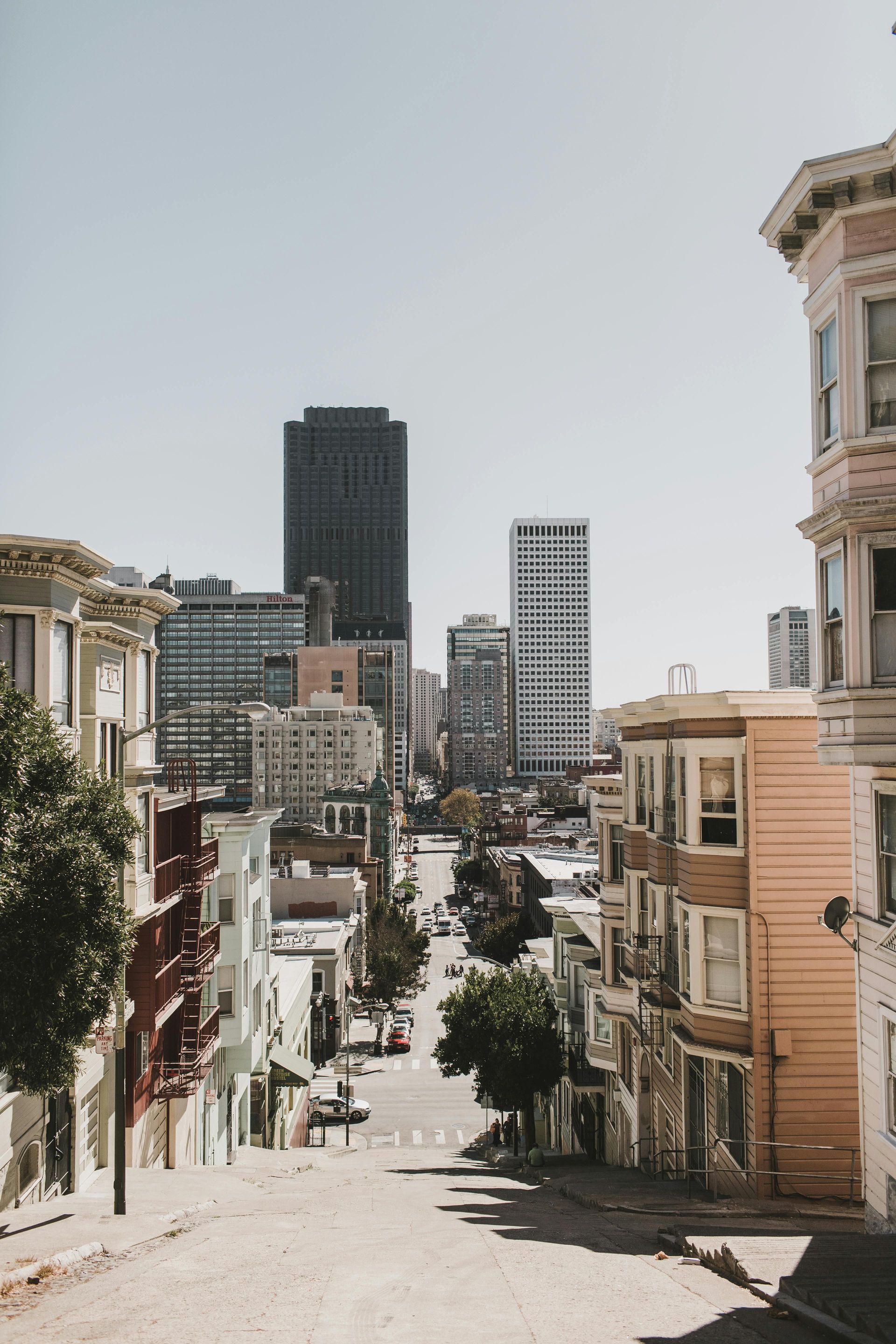 San Francisco street scene with colorful Victorian houses lining a steep hill leading to city buildings.
