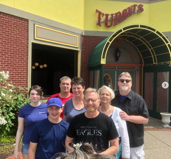 A group of people standing in front of a building that says turones