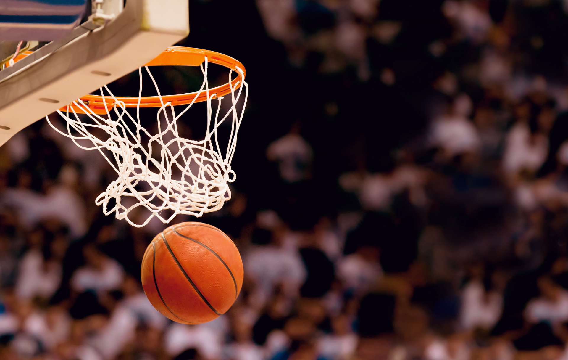 A basketball is going through a hoop during a game