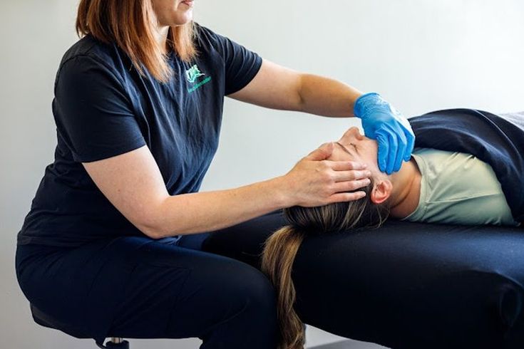 A woman is giving a massage to a patient laying on a table.