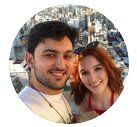 Casal sorridente, homem e mulher, tirando uma selfie com o horizonte da cidade ao fundo.