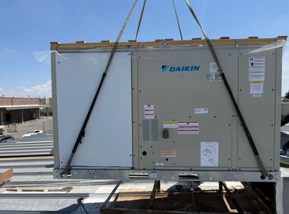 Outdoor HVAC condenser units on a rooftop beside a blue ventilation duct under a clear sky