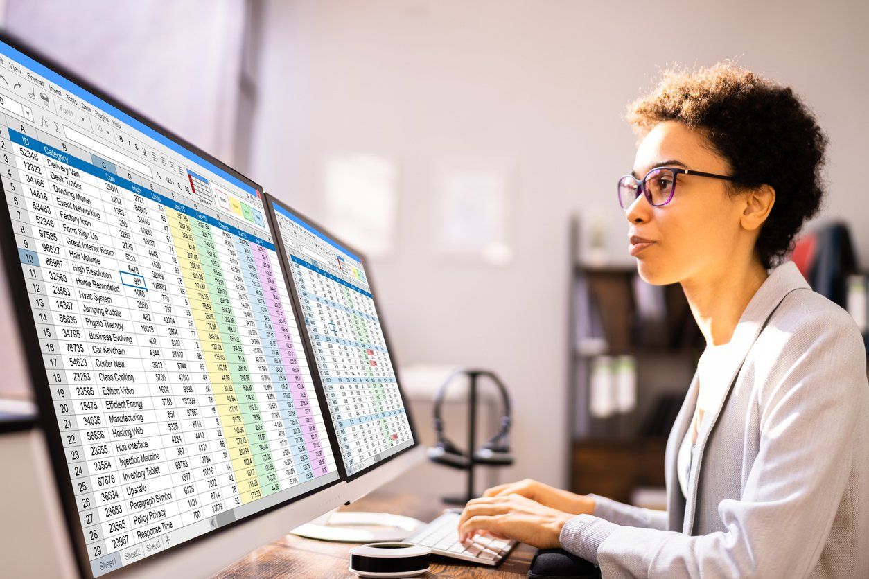 a woman is sitting at a desk in front of two computer monitors .