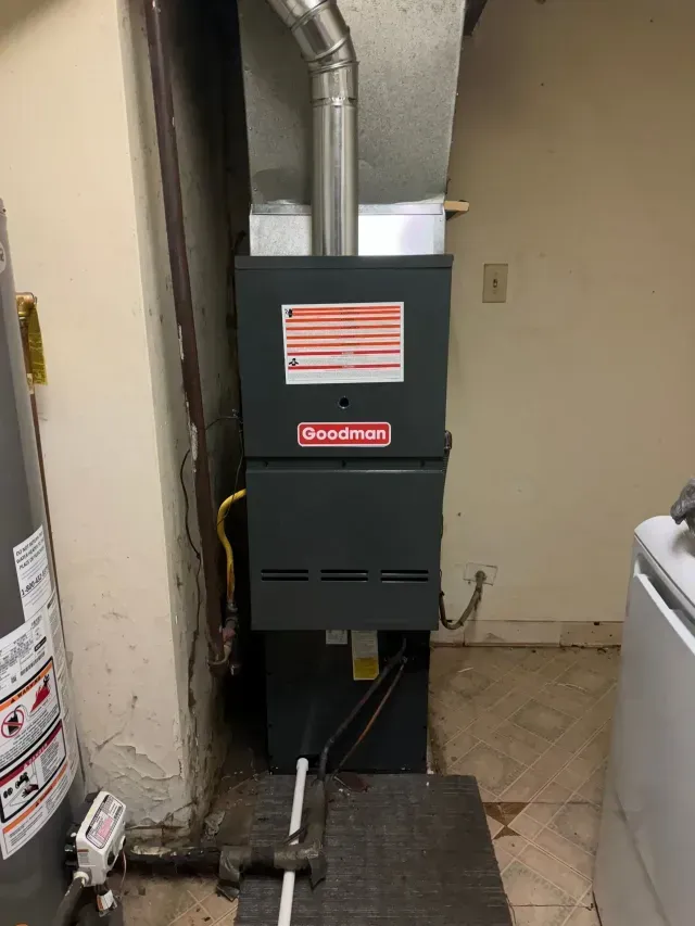 Goodman furnace in a basement setting with a water heater and washing machine.