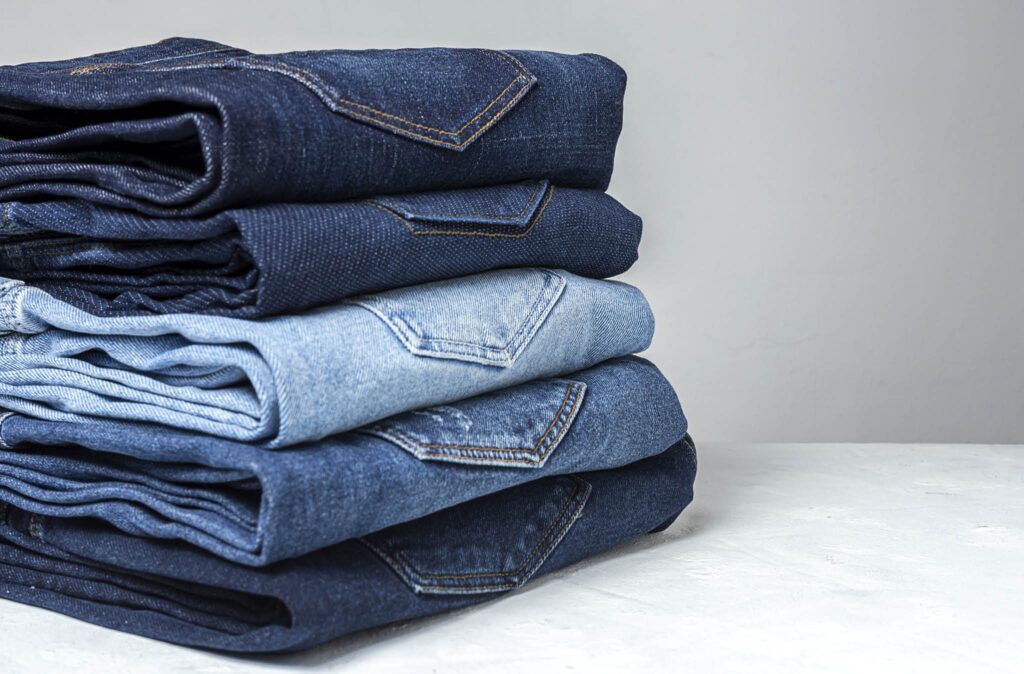 A stack of jeans is sitting on top of each other on a table.
