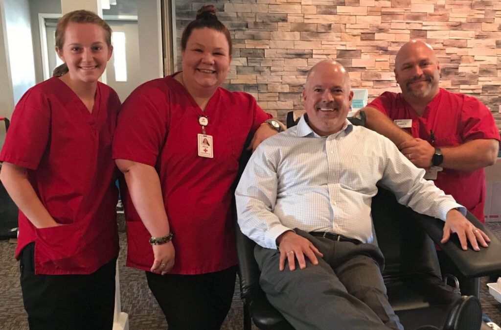 A group of people are posing for a picture with a man in a wheelchair.