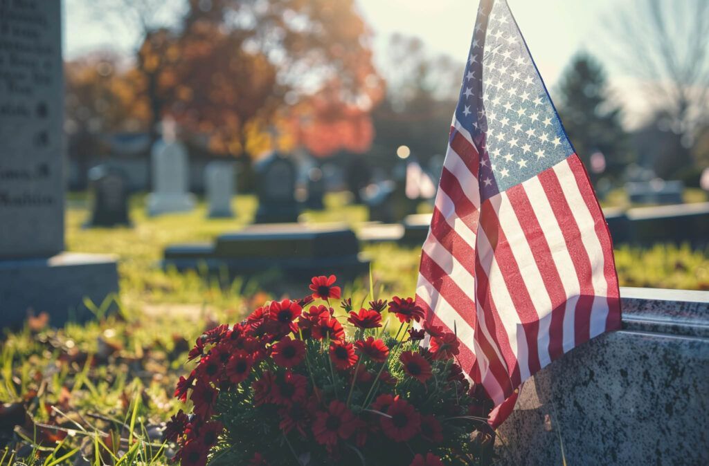 An american flag is sitting on top of a grave in a cemetery.