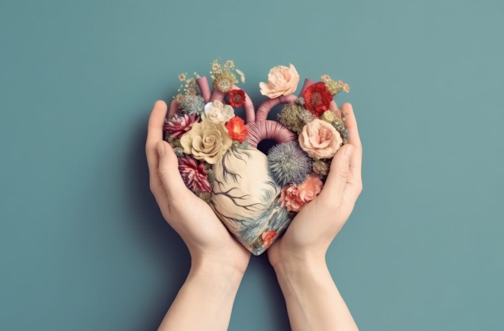 A person is holding a heart made of flowers in their hands.