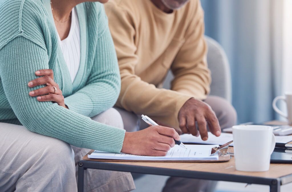 A man and a woman are sitting at a table signing a document.