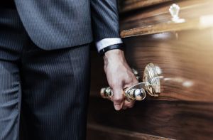 A man in a suit is holding the handle of a coffin.