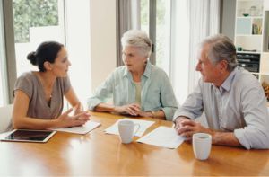 A woman is sitting at a table with two older people.