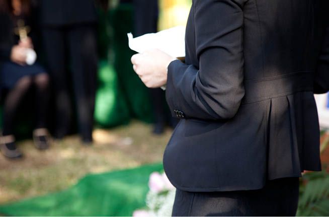A woman in a black suit is holding a piece of paper