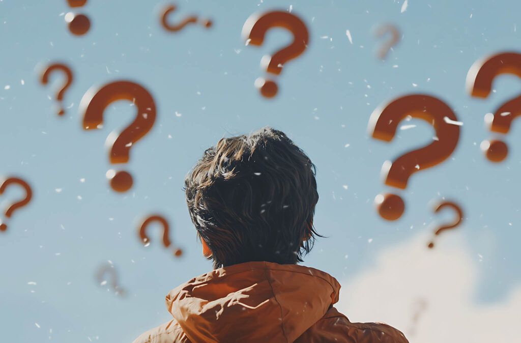 A person is looking up at a bunch of question marks flying in the sky.
