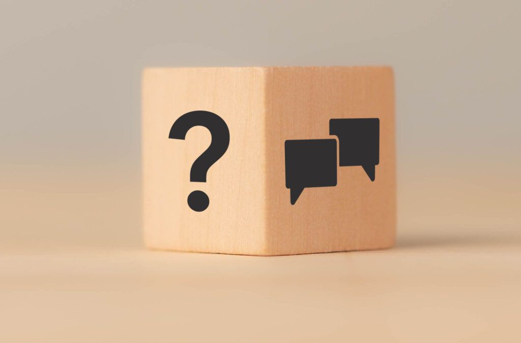 A wooden block with a question mark and two speech bubbles on it.
