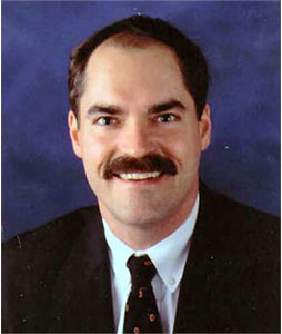 A man with a mustache is wearing a suit and tie