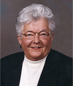 A woman wearing glasses and a black jacket smiles for the camera