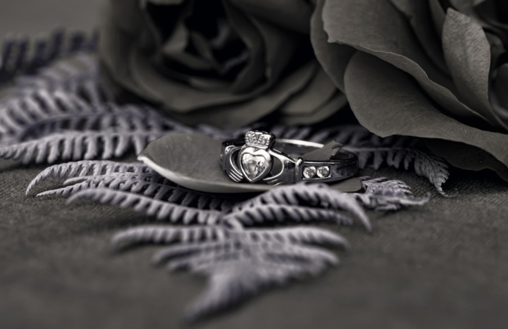 A black and white photo of a wedding ring and a rose.