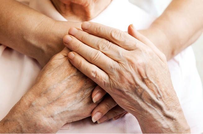A woman is holding the hands of an older woman.