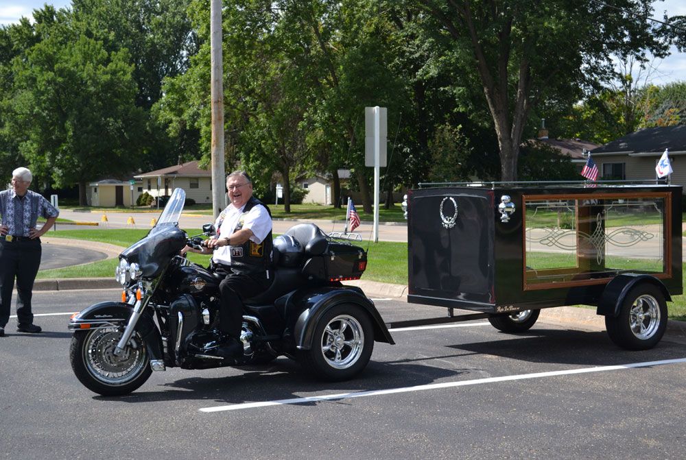 A man is riding a motorcycle with a trailer attached to it.