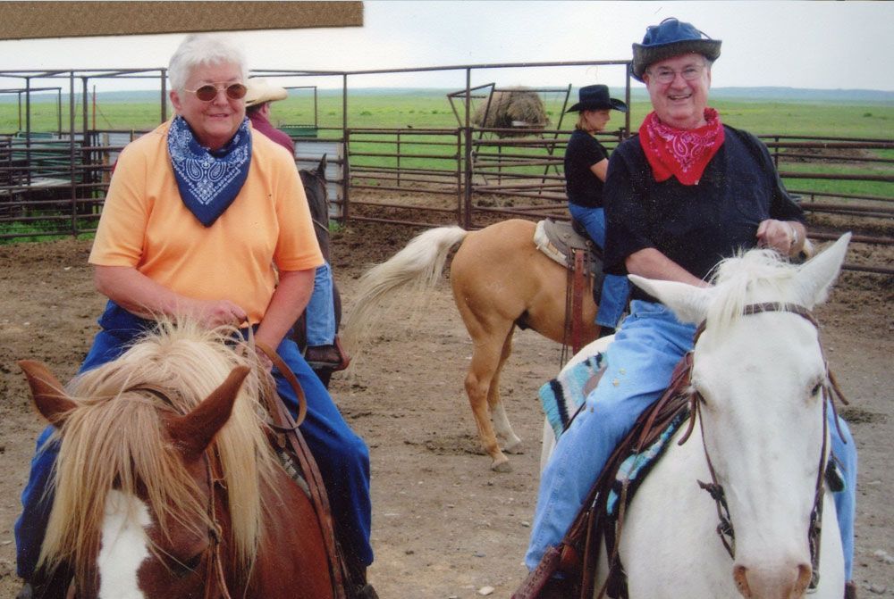 Two men are riding horses in a fenced in area